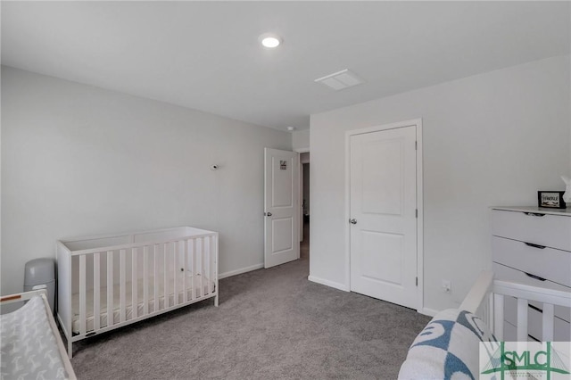 carpeted bedroom featuring a nursery area