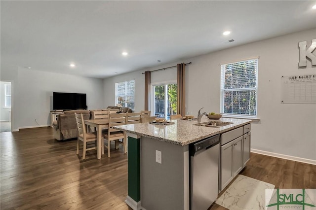 kitchen with dark wood-type flooring, a center island with sink, stainless steel dishwasher, and sink