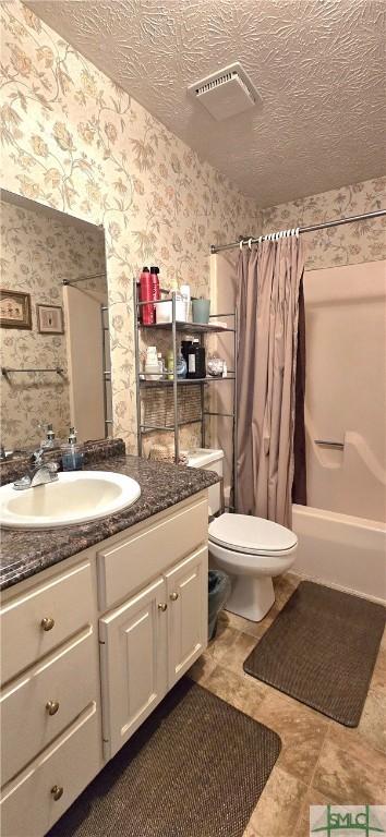 full bathroom with shower / tub combo with curtain, vanity, toilet, and a textured ceiling