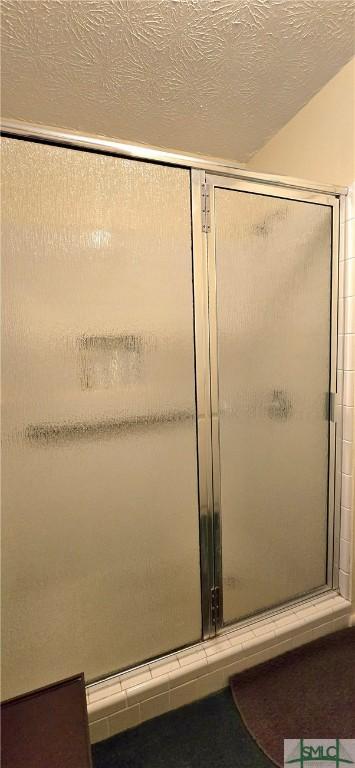 bathroom featuring a textured ceiling and a shower with shower door