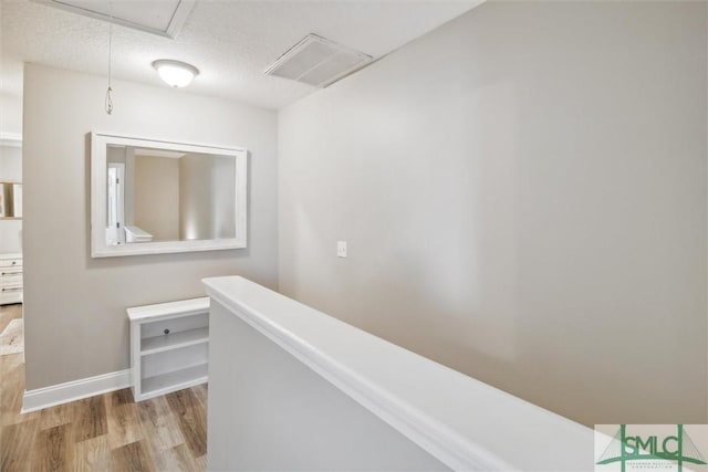 hallway with a textured ceiling and light hardwood / wood-style flooring