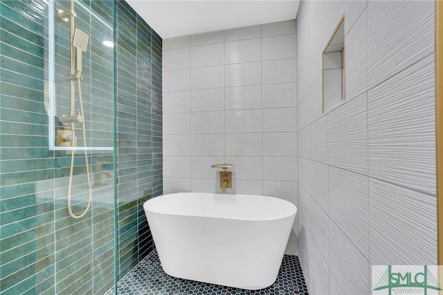 bathroom featuring tile patterned flooring, a bathtub, and tile walls