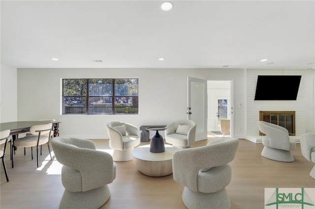 living room with plenty of natural light, wood-type flooring, and a brick fireplace