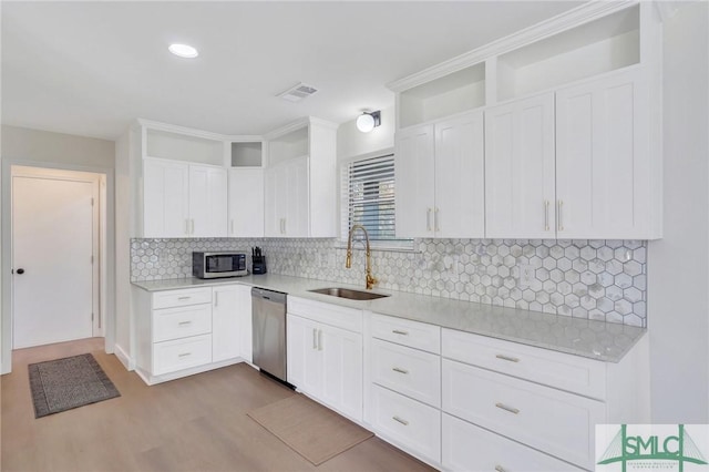 kitchen with sink, stainless steel appliances, light hardwood / wood-style floors, decorative backsplash, and white cabinets