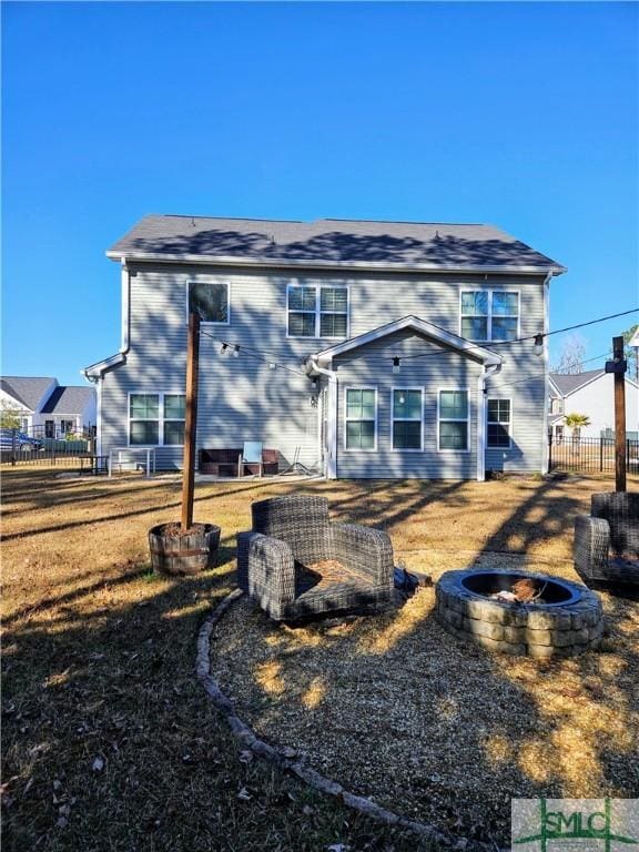 back of house with a yard and an outdoor fire pit