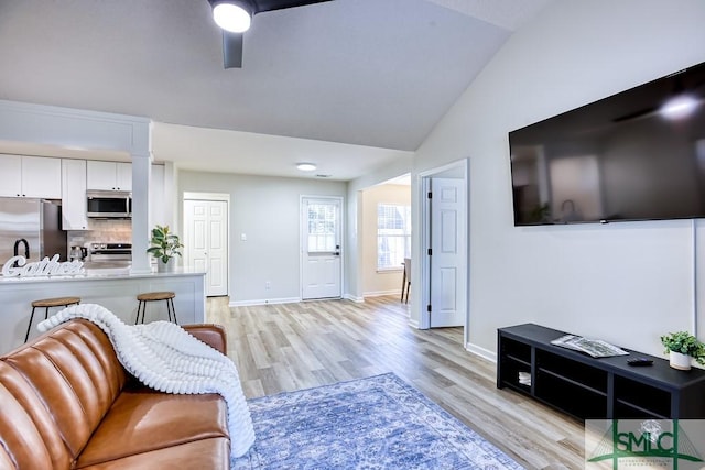 living room with lofted ceiling, ceiling fan, and light hardwood / wood-style flooring