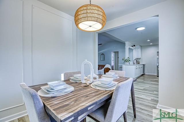 dining area featuring vaulted ceiling and light hardwood / wood-style flooring