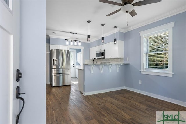 kitchen with white cabinets, crown molding, appliances with stainless steel finishes, a kitchen bar, and kitchen peninsula