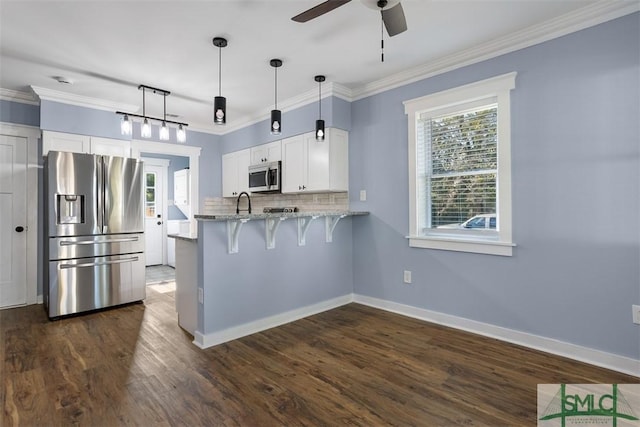 kitchen with kitchen peninsula, stainless steel appliances, dark wood-type flooring, white cabinetry, and a breakfast bar area