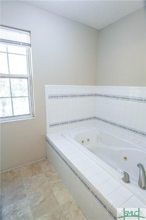 bathroom featuring a textured ceiling and a relaxing tiled tub