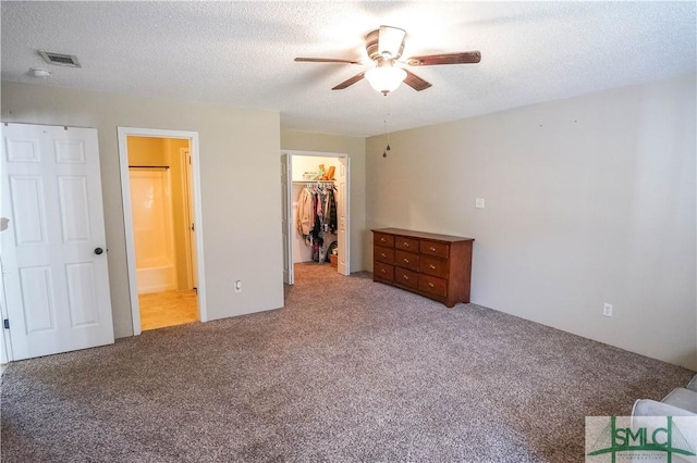 unfurnished bedroom with connected bathroom, ceiling fan, a spacious closet, carpet floors, and a closet