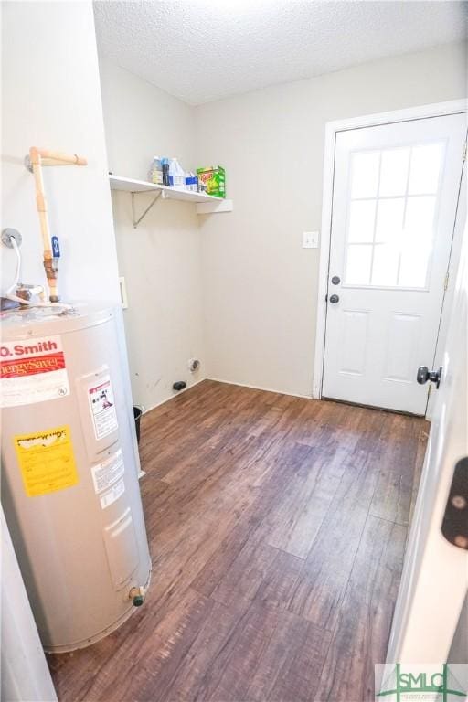 clothes washing area featuring wood-type flooring, electric water heater, and a textured ceiling