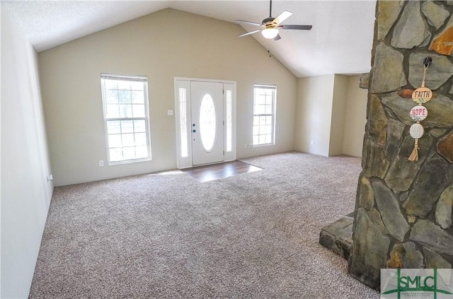 foyer entrance with carpet floors, vaulted ceiling, a wealth of natural light, and ceiling fan