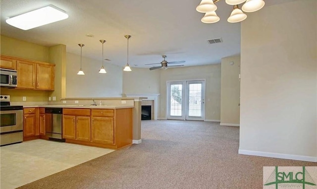 kitchen featuring light carpet, appliances with stainless steel finishes, kitchen peninsula, ceiling fan with notable chandelier, and hanging light fixtures