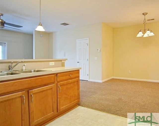 kitchen featuring light carpet, sink, hanging light fixtures, and ceiling fan with notable chandelier