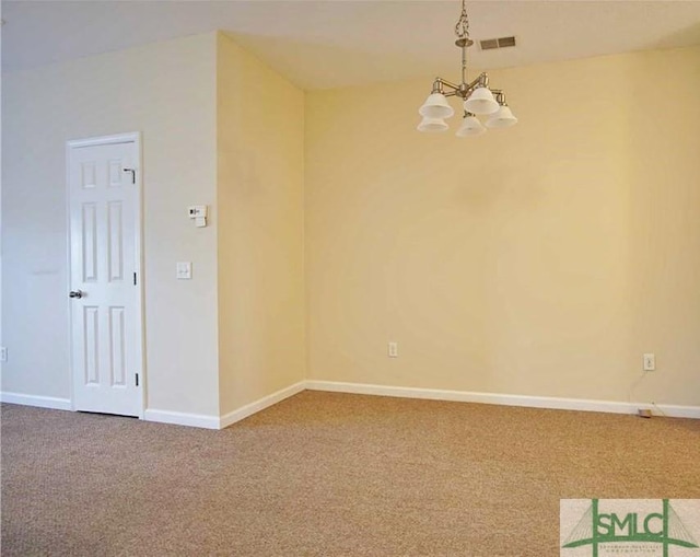 spare room featuring carpet floors and an inviting chandelier