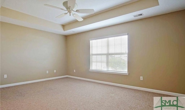 spare room with a raised ceiling, ceiling fan, and carpet flooring