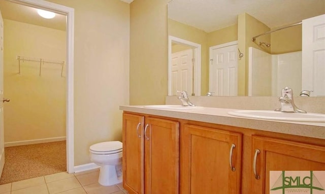 bathroom with toilet, vanity, tile patterned floors, and walk in shower