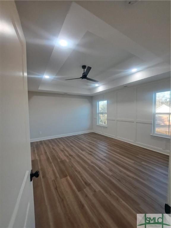 empty room with a tray ceiling, ceiling fan, and dark hardwood / wood-style floors