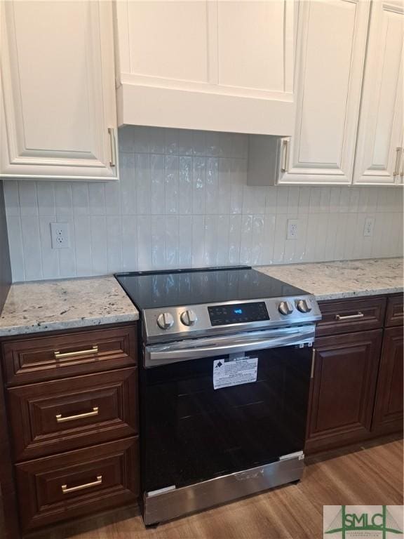 kitchen with light wood-type flooring, tasteful backsplash, stainless steel range with electric stovetop, dark brown cabinetry, and white cabinets