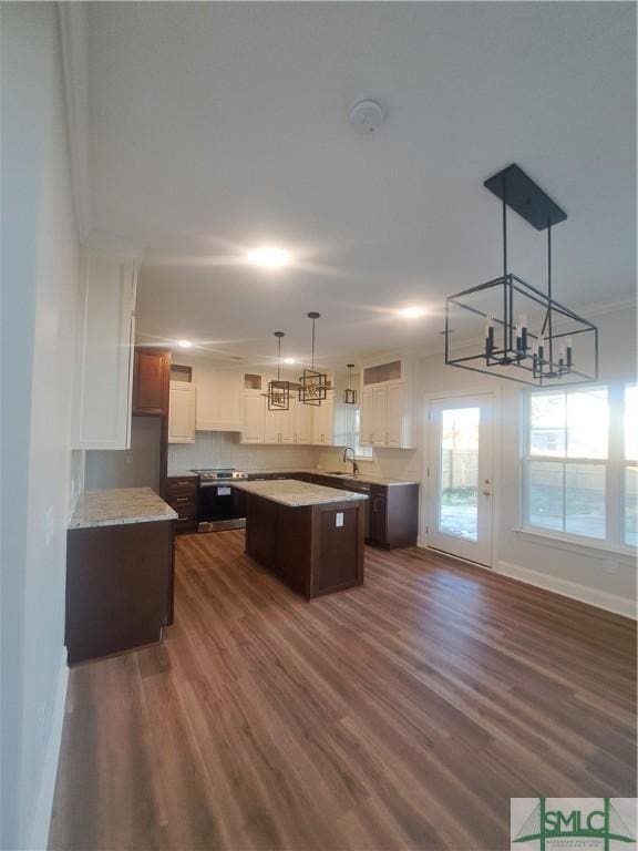 kitchen with sink, dark hardwood / wood-style floors, pendant lighting, dark brown cabinets, and a kitchen island