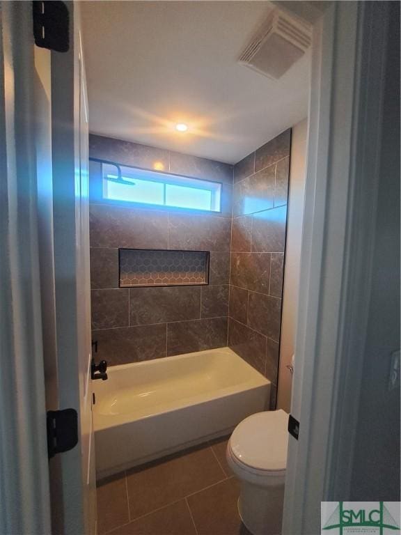 bathroom featuring tile patterned floors, tiled shower / bath combo, and toilet