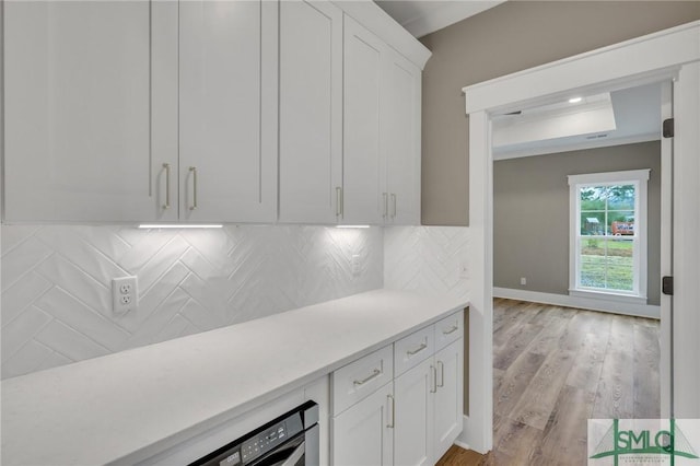 bar with decorative backsplash, light hardwood / wood-style floors, and white cabinetry