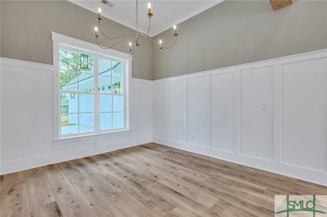 unfurnished dining area featuring crown molding, light hardwood / wood-style floors, and a notable chandelier