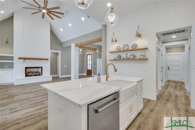 kitchen with light stone countertops, dishwasher, sink, an island with sink, and white cabinets