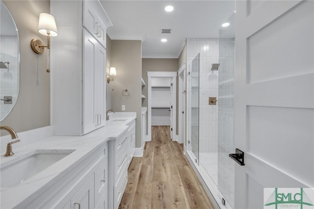 bathroom featuring crown molding, vanity, a shower with shower door, and wood-type flooring