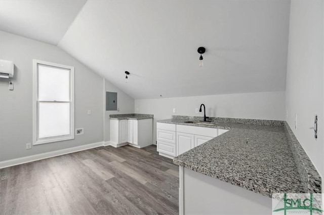 kitchen featuring light wood-style flooring, white cabinets, a sink, and a peninsula