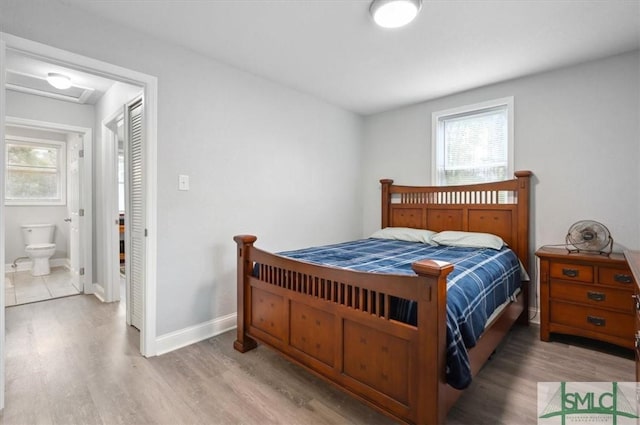 bedroom with multiple windows, wood finished floors, and attic access