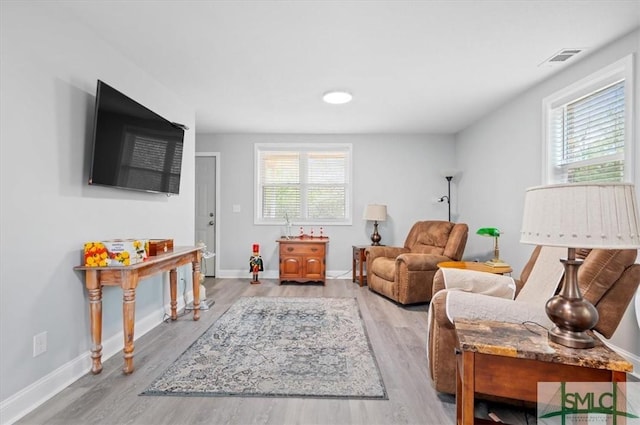 sitting room featuring light wood-type flooring, visible vents, and baseboards