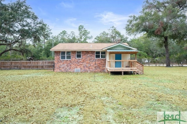 rear view of property with crawl space, a yard, fence, a wooden deck, and brick siding