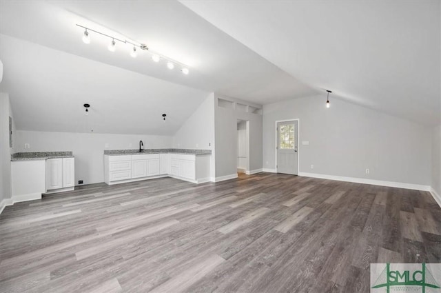 bonus room with vaulted ceiling, wet bar, light wood-style flooring, and baseboards