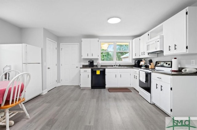 kitchen with dark countertops, light wood-style floors, white cabinetry, a sink, and white appliances