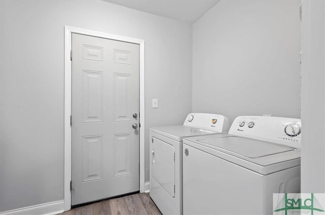 washroom with laundry area, baseboards, light wood finished floors, and washing machine and clothes dryer