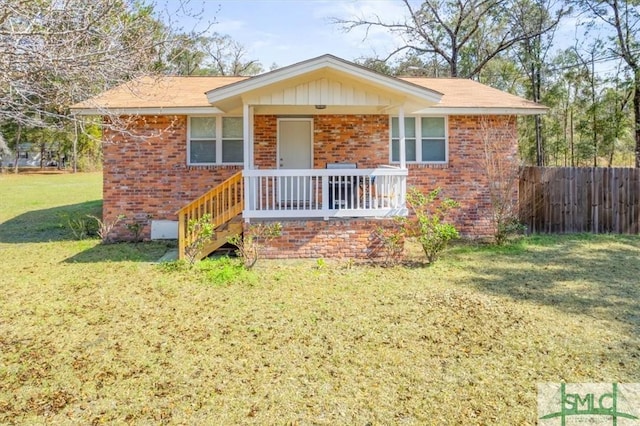 ranch-style house featuring covered porch, brick siding, fence, and a front lawn