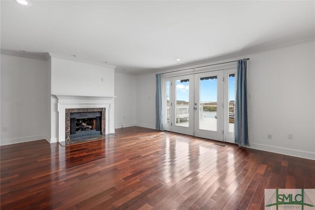 unfurnished living room with french doors, crown molding, and dark wood-type flooring