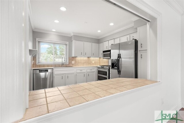 kitchen featuring tile countertops, sink, appliances with stainless steel finishes, tasteful backsplash, and white cabinetry