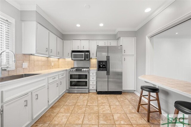 kitchen featuring light tile patterned floors, stainless steel appliances, white cabinetry, and sink