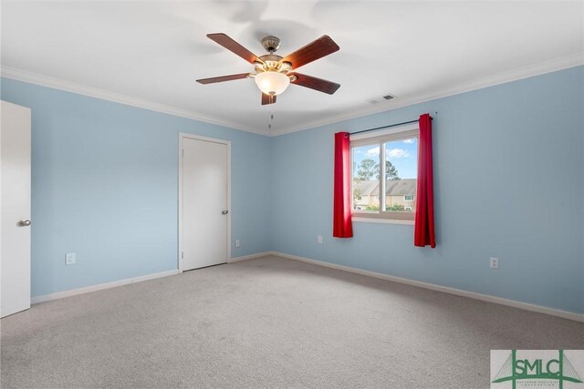 empty room featuring crown molding, carpet floors, and ceiling fan