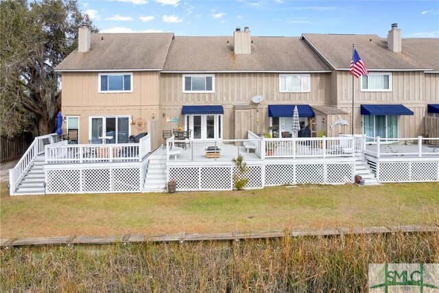 back of property featuring a deck and a lawn