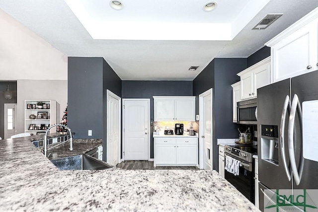 kitchen with light stone countertops, stainless steel appliances, white cabinetry, and sink