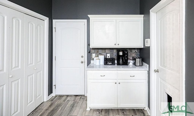 kitchen with decorative backsplash, light wood-type flooring, and white cabinetry