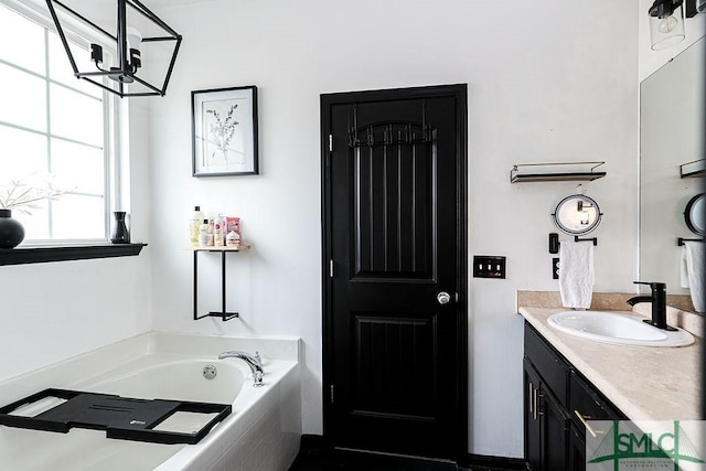 bathroom featuring vanity, a relaxing tiled tub, and an inviting chandelier