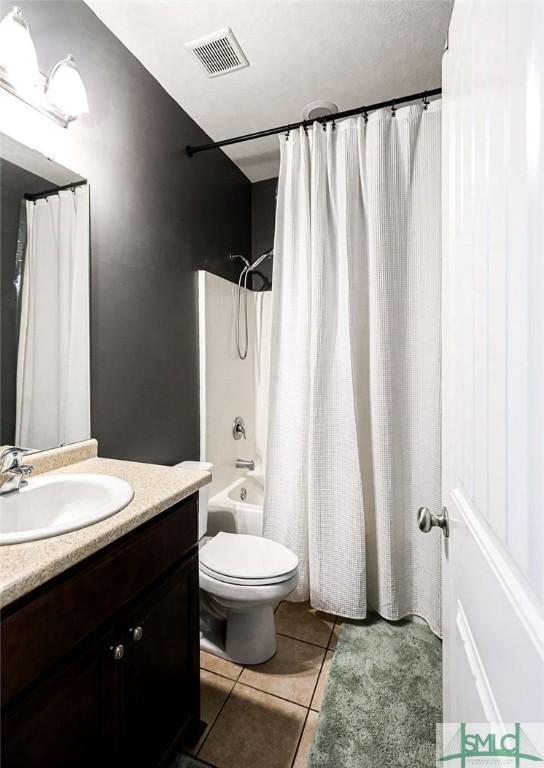 full bathroom featuring tile patterned flooring, shower / bath combination with curtain, vanity, and toilet