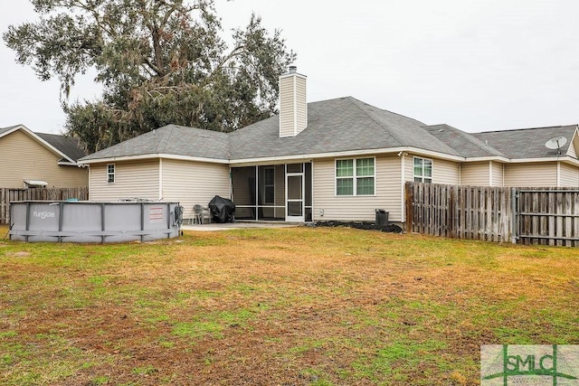 back of property featuring a sunroom, a fenced in pool, and a yard