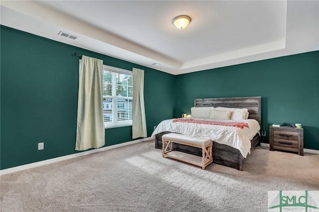 carpeted bedroom with a raised ceiling