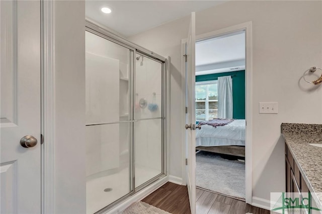 bathroom with wood-type flooring, vanity, and a shower with door